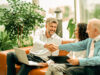 Consulting: Consultant and client couple shaking hands in front of a laptop.