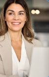 Una donna sorridente davanti al laptop scopre le diverse funzioni di onOffice Enterprise.